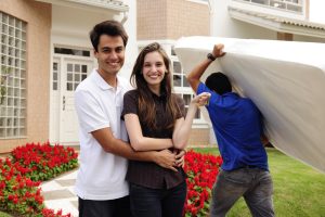 Moving home couple in front of new house