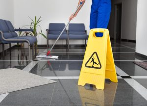 cleaner mopping floor with safety sign
